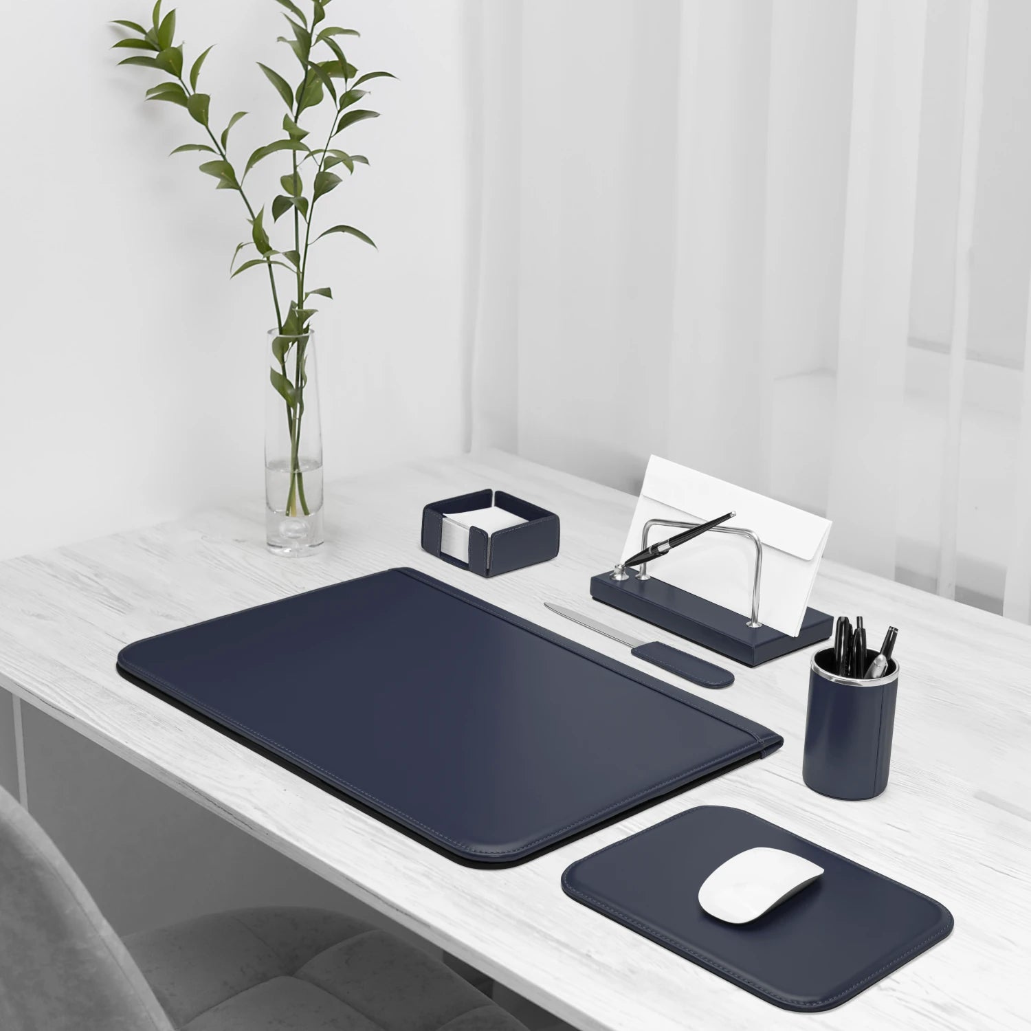 Dark blue desk accessories on a white desk, including a mouse pad and pen holder.
